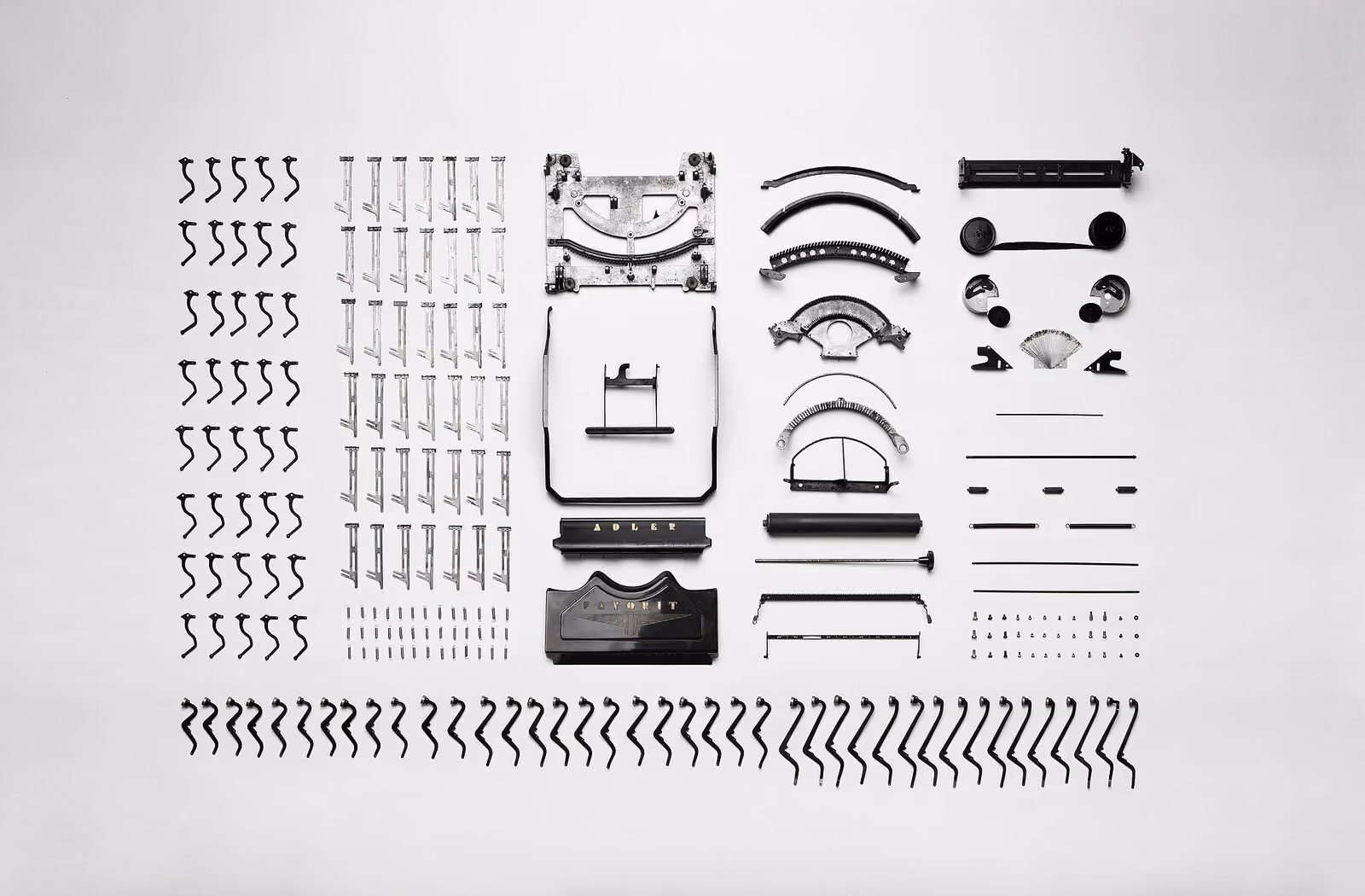 A typewriter taken apart, every piece laid out in rows.
